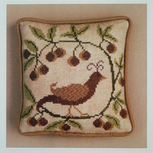 May include: A cross-stitch pattern featuring a brown bird surrounded by cherries and green leaves, with the text "O Birdy" and "La-D-Da designs for counted thread". The design is on a square pillow.