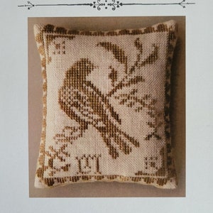 May include: A cross-stitch pattern for a pillow featuring a brown bird on a branch with the text "Yellow Bird" and "La-D-Da designs for counted thread".