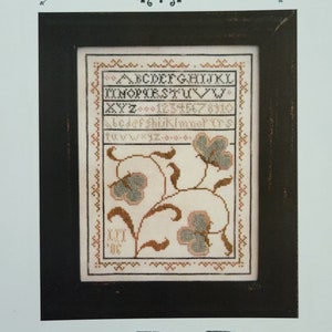May include: A cross stitch pattern sampler with a black frame. The pattern features a floral design with green and pink flowers and leaves. The text "A Big Flower Sampler" is at the top of the image. The text "La-D-Da designs for counted thread" is at the bottom of the image.