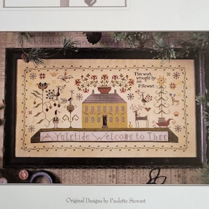 May include: A cross-stitch pattern featuring a house with a yellow exterior and a red roof, surrounded by trees and a deer with a sleigh. The text "A Yuletide Welcome to Thee" is stitched below the house. The work was wrought by P. Stewart.