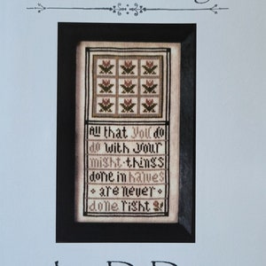 May include: A cross stitch pattern with a black frame and white background. The pattern features a floral design with pink and green flowers and the text "All that you do with your might things done in halves are never done right". The title of the pattern is "With Your Might" and the designer is "La-D-Da".