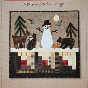 May include: A quilting pattern titled "Woodland Visitors" by Norma Whaley. The pattern features a snowman, deer, bear, and trees. The finished size is 18 inches by 19 inches.