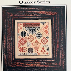 May include: A framed cross-stitch sampler titled "Obedience" from the "Quaker Series." The design features geometric patterns, floral motifs, and the numbers 1-9. The color palette includes red, black, and beige. The frame is a dark brown.