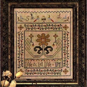 May include: A framed cross-stitch sampler with a floral design and the text "Live & Let Live - 1911". The sampler is in a brown wooden frame with a decorative border.