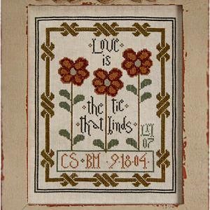 May include: Cross stitch embroidery with a floral design and the text "Love is the tie that binds". The design features three orange flowers with green stems and leaves. The text is in a brown font and the date "CS BM 9-18-04" is below the text.