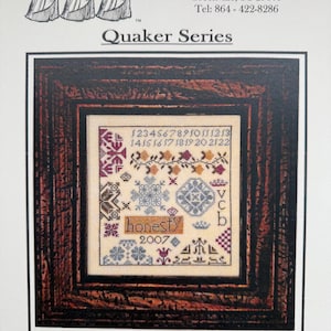 May include: A framed cross-stitch pattern titled "Honesty" from the "Quaker Series." The design features floral and geometric motifs, numbers, and the word "honesty" with the year 2007. The frame is a dark, textured wood.