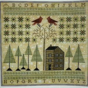 Può includere: Campione a punto croce con una scena invernale. Due uccelli rossi si posano su un albero spoglio sopra una casa e alberi sempreverdi. Il disegno include motivi a stella verdi e rossi, e l'alfabeto è cucito sopra e sotto.
