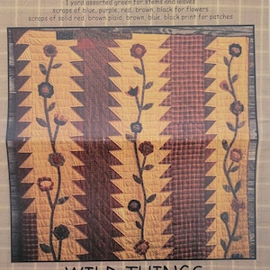 May include: A quilt pattern called "Wild Things" by Primitive Pieces by Lynda. The pattern features a geometric design with a brown, yellow, and red color scheme. The quilt is 60 inches by 70 inches.