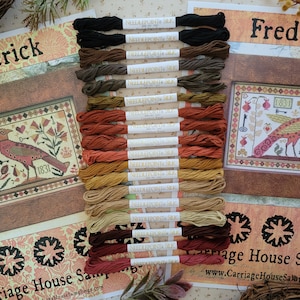 May include: A set of 20 embroidery floss spools in shades of brown, orange, red, and beige. The floss is labeled "Needlepoint Silk". The floss is arranged in a vertical row. The image also includes a framed cross-stitch pattern with a bird and the text "Frederick 1831" and "Frederika 1831".
