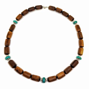 May include: A brown wooden bead necklace with turquoise accents. The necklace is made of cylindrical beads and has a silver clasp.