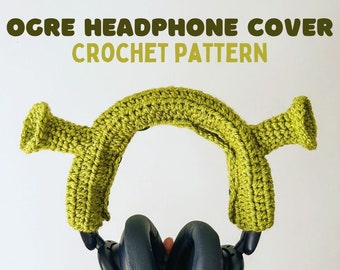 May include: Green crocheted headphone cover with ears shaped like the character Shrek. The cover is on a pair of black headphones.