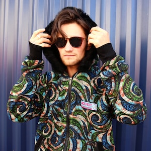Puede incluir: Una sudadera con capucha negra con un estampado abstracto colorido. El estampado presenta remolinos de verde, azul y marrón. La sudadera tiene una cremallera y una capucha negra con forro de piel. El texto "REPRINT" es visible en la parte delantera de la sudadera.