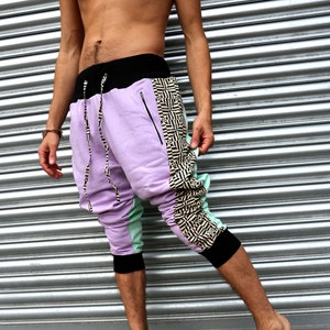 May include: Purple, green, and black patterned pants with a drawstring waist and zippered pockets.