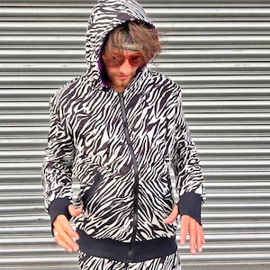 May include: A black and white zebra print hooded sweatshirt with a zip closure. The sweatshirt has a black waistband and cuffs.