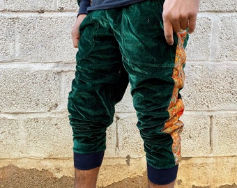Puede incluir: Pantalón de terciopelo verde con una raya lateral estampada. El pantalón tiene una cintura y puños negros.