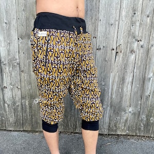 Puede incluir: Un pantalón de color marrón y negro con un patrón geométrico. Tiene una cintura negra y un cordón de ajuste. El pantalón es corto.