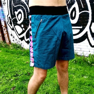 Puede incluir: Pantalones cortos deportivos azul turquesa con cintura negra y estampado geométrico rosa y blanco en el lateral.