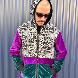May include: A black, white and purple hooded jacket with a zip fastening. The jacket has a geometric pattern on the front and velvet sleeves.