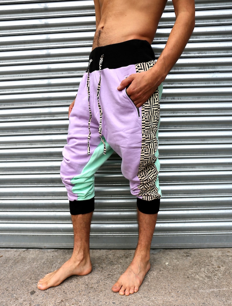 May include: Purple and green patterned pants with black trim and a black waistband. The pants have a geometric pattern on the side.