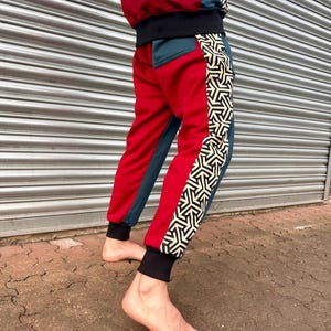 May include: Red and teal sweatpants with a black waistband and a geometric pattern on the side.