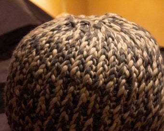 Pouf rond tricoté à la main avec un gros fil gris et blanc