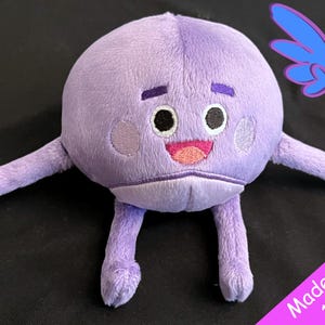 May include: Purple plush toy with a round body and long arms. The toy has a smiling face with black eyes and a pink mouth. The toy is made to order and takes 1-2 weeks to ship. "Guardian Earth Plush" is written on the background.