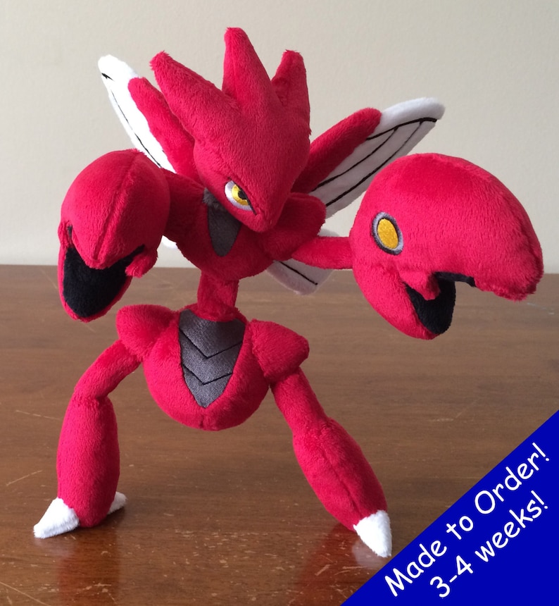 K&ouml;nnte beinhalten: Rotes und schwarzes Pl&uuml;schtier eines Pokemon-Charakters mit gro&szlig;en Krallen und Fl&uuml;geln. Das Spielzeug steht auf einer Holzoberfl&auml;che. Auf Bestellung! 3-4 Wochen!