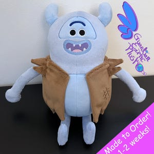 May include: A light blue plush toy character with a brown vest and a smiling face. The plush has two small horns and long arms. The text "Guardian Earth Plus" and "Made to Order! 1-2 weeks!" are visible.