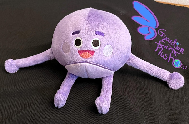 Puede incluir: Juguete de peluche morado con un cuerpo redondo y dos brazos largos. El juguete tiene una cara sonriente con dos ojos, una nariz y una boca. El juguete est&aacute; etiquetado como "Guardian Earth Plush" en el lado derecho.