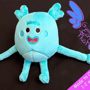 May include: A light blue plush toy with a friendly face and four arms. The toy is made to look like a cartoon character. The text "Guardian Earth Plush" is visible in the background.