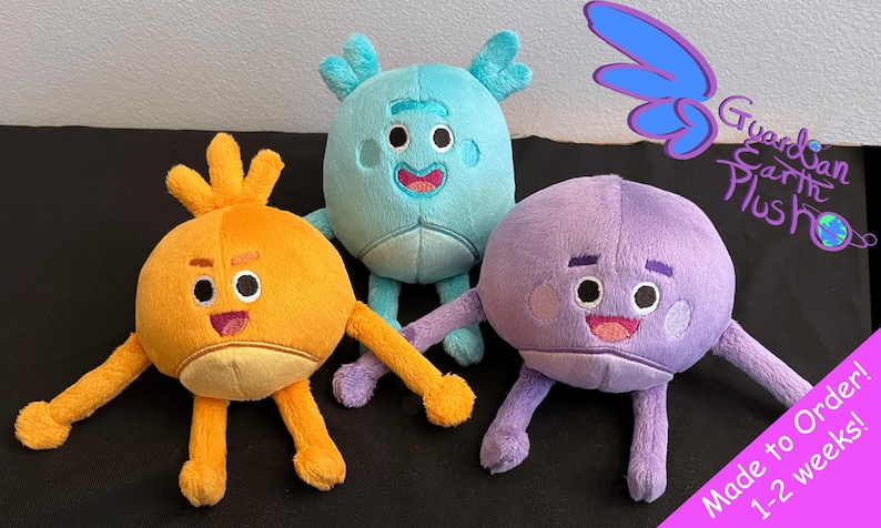 Puede incluir: Tres peluches, cada una con un color y dise&ntilde;o diferente. El primer juguete es naranja con una cara sonriente y un pelo naranja puntiagudo. El segundo juguete es azul claro con una cara sonriente y dos cuernos. El tercer juguete es morado con una cara sonriente y un cuerpo redondo. Los juguetes est&aacute;n hechos por Guardian Earth Plush y est&aacute;n disponibles para ordenar.
