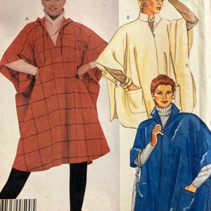 Puede incluir: Patrón de costura vintage con tres diseños de poncho. Uno es un tartán color óxido con capucha. Otro es un poncho color crema con cremallera y bolsillos. El tercero es un poncho azul con cremallera y bolsillos.