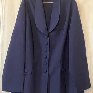 May include: A navy blue blazer with a shawl collar and six matching buttons down the front. The blazer has two front pockets and long sleeves. The label reads "ALLISON TAYLOR". The blazer is hanging on a silver hanger.