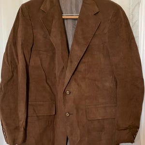 Puede incluir: Una chaqueta de pana marrón con cierre de tres botones y dos bolsillos de solapa.