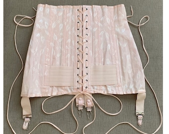May include: A light pink corset with a floral pattern. The corset has vertical boning, a lace-up front, and garter straps. The fabric has a subtle sheen, and the overall design is vintage-inspired.