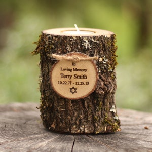 May include: A cylindrical wooden log candle holder with natural bark and green moss. A small circular wood slice is tied to the front with twine, engraved with "In Loving Memory Terry Smith 10.22.71 - 12.28.18" and a Star of David.