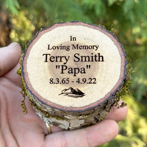 May include: A wooden memorial plaque with the text "In Loving Memory Terry Smith "Papa" 8.3.65 - 4.9.22" and a mountain silhouette.