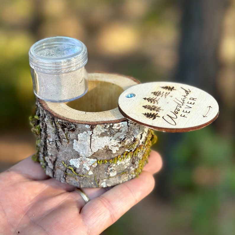 Pu&ograve; includere: Una piccola scatola di legno con un coperchio che dice "Woodland Fever" e un piccolo barattolo trasparente all'interno. La scatola &egrave; fatta per assomigliare a un tronco d'albero.