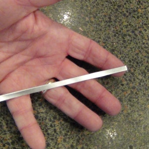May include: A silver metal rod held in a person's hand.
