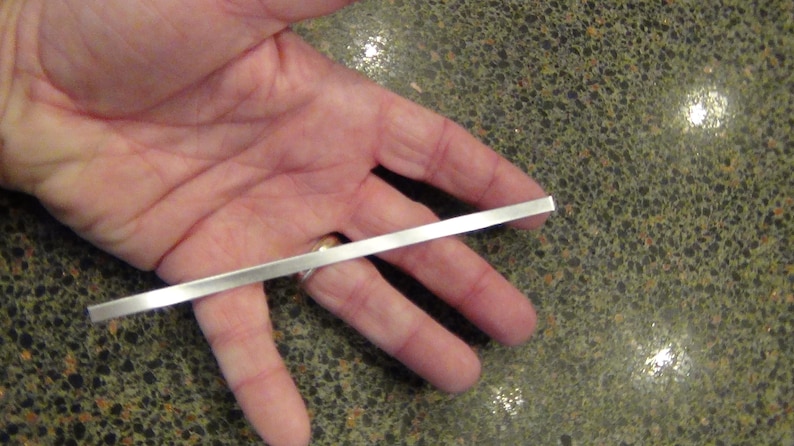 May include: A silver metal rod held in a person's hand.