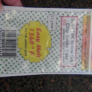 以下が含まれることがあります： 透明なプラスチックバッグには、14Kイエローゴールドチップはんだが入っています。 バッグには「Easy Melt 1340&deg;F」と「50個1x1x1/4 mm」と書かれています。 バッグは手で持たれています。