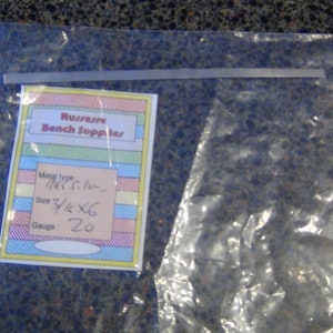 May include: A clear plastic bag with a label that says "Russwin Bench Supplies". The label has a yellow, pink, blue, and white striped background. The label also includes the following information: Metal type: 1/4" St. Steel, Size: 3 1/2" x 6, Gauge: 20.
