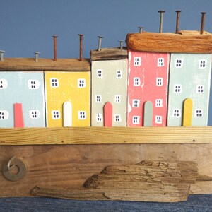 Cottage e case colorati su legni con tetti in legni e affascinanti finestre e porte dipinte, decorazioni su scaffali in riva al mare, scena costiera