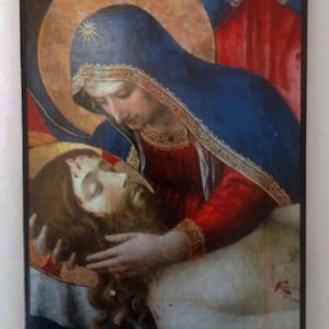 May include: A rectangular religious painting depicting a figure in a blue hooded cloak and red garment cradling the head of a bearded figure with long brown hair. Both figures have golden halos against a dark background with red accents.