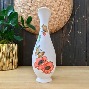 May include: White ceramic vase with a pearlescent finish, featuring a hand-painted design of orange poppies and butterflies.