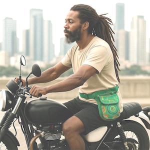 May include: A person on a black motorbike, wearing a green fanny pack with a colourful circular design. The person is wearing a beige t-shirt and black shorts. A cityscape forms the background.