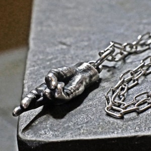Ręka ze skrzyżowanymi palcami, srebrny naszyjnik w stylu vintage, amulet przynoszący szczęście
