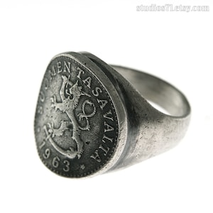 May include: A silver ring with a vintage coin design featuring a lion and the text "SUOMEN TASAVALTA 1963".