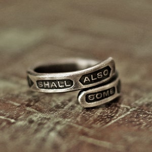 May include: A silver ring with the words "SHALL ALSO COME" engraved on it.