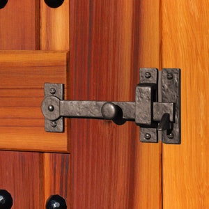 May include: A black metal door latch with a lever handle and a rectangular plate. The latch is mounted on a wooden door.